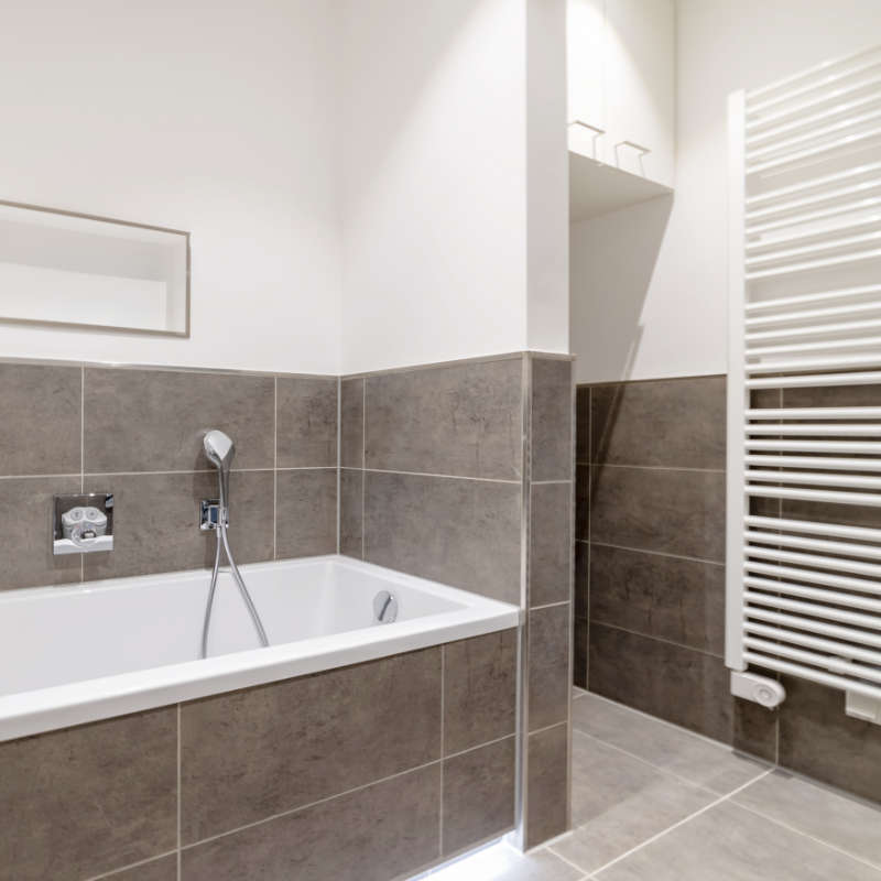 Ein frisch saniertes Badezimmer mit Badewanne und Handtuchheizkörper