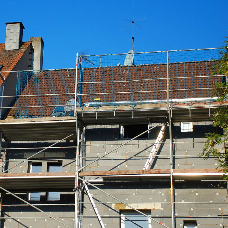 Das Bild zeigt die eingerüstete Fassade eines renovierungsbedürftigen Hauses.